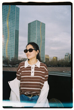 Portrait of Young Woman in Sunglasses with City Background