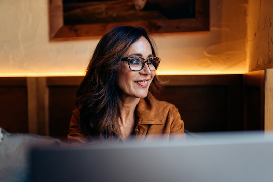 Mature woman smiling while working remotely indoors