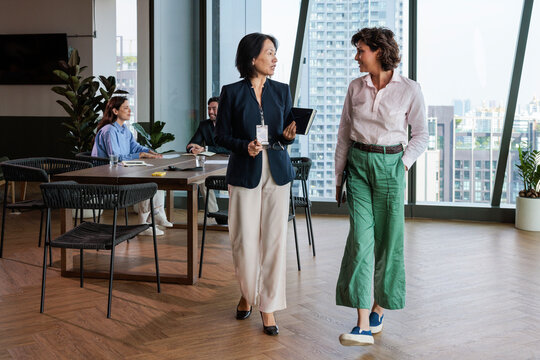 Businesswomen discuss strategy in modern office with city view.