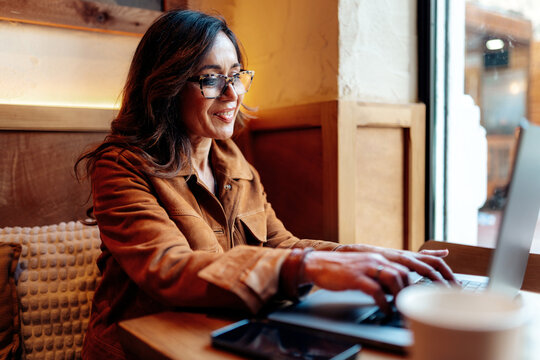 Woman working remotely with laptop in cafe