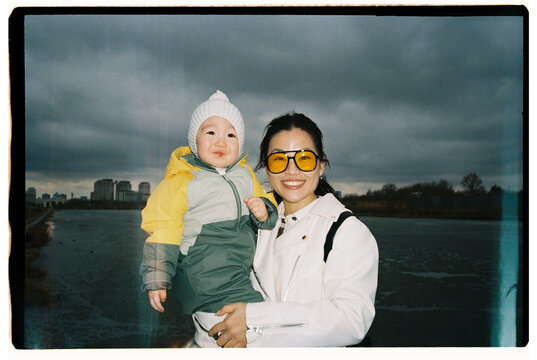 Happy Mother Holding Baby Outdoors