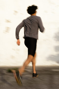Young man running in motion blur along urban street