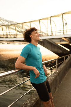 Young man resting by riverside railing at golden hour