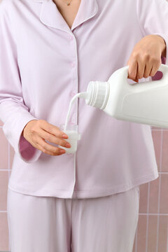 Woman in pajamas pouring liquid detergent into a measuring cap