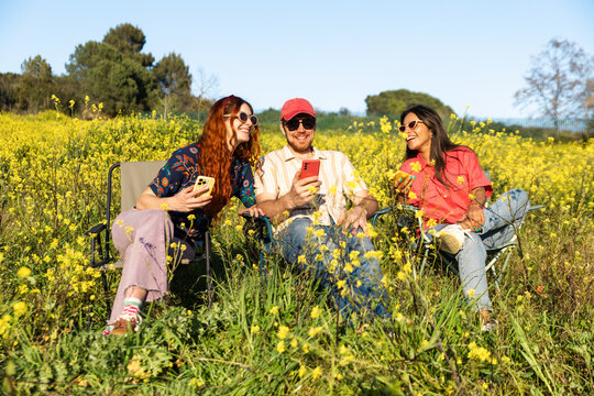 Friends Using Phone In Flower Field