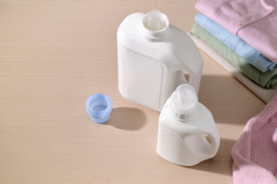 Two white laundry detergent bottles with a blue cap and folded clothes
