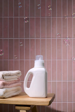 Laundry detergent bottle with clean folded towels and floating bubbles
