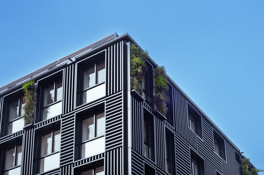 Modern building facade with vertical garden balconies and metal claddi