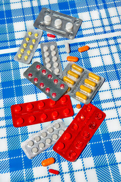 Assorted pills and blister packs on blue checkered background