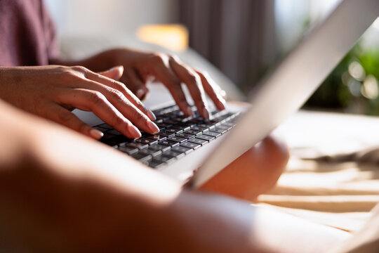 Hands typing on a laptop keyboard in soft light.
