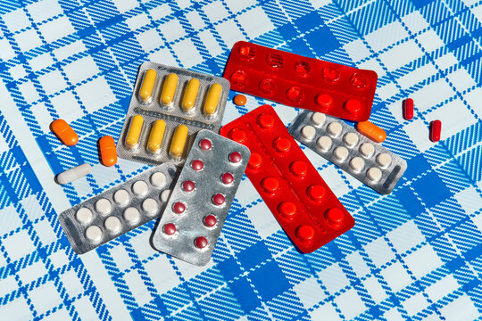 Assorted pills and blister packs on blue checkered background