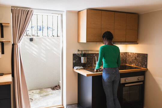 Woman in Kitchen by Basement Apartment Entrance