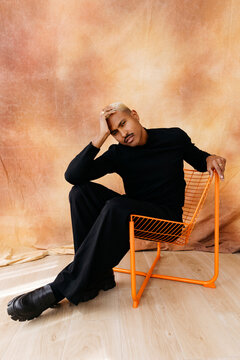 Mnek sitting on orange chair in studio