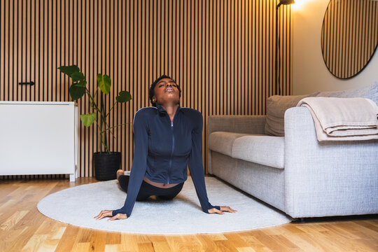 African Woman Doing Yoga Cobra Pose in Modern Small Apartment