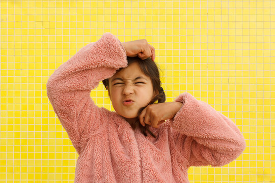 Child Making a Funny Face in Front of a Yellow Wall