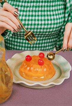 Orange jelly dessert with cherries on plates with spoon and fork