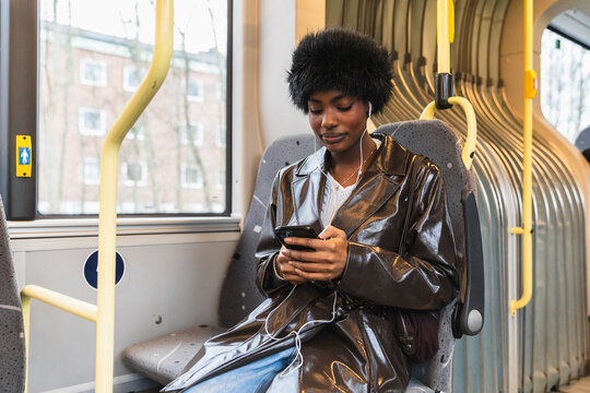 Black Woman Using Smartphone While Commuting on Public Bus