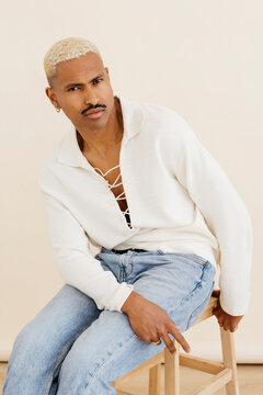Man posing wearing white pullover and jeans