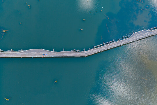 Derelict wooden bridge over sky reflections on a calm inland river