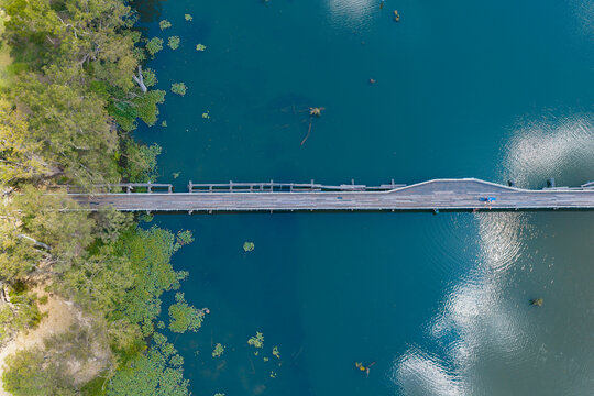 Derelict wooden bridge over sky reflections on a calm inland river