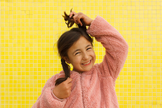 Smiling Girl Holds Her Hair in Playful Pose