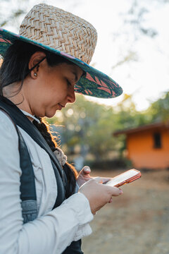 Woman wearing straw hat typing on smartphone outdoor