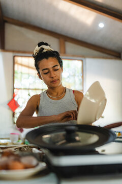 Young woman cooking food in home kitchen pouring mixture