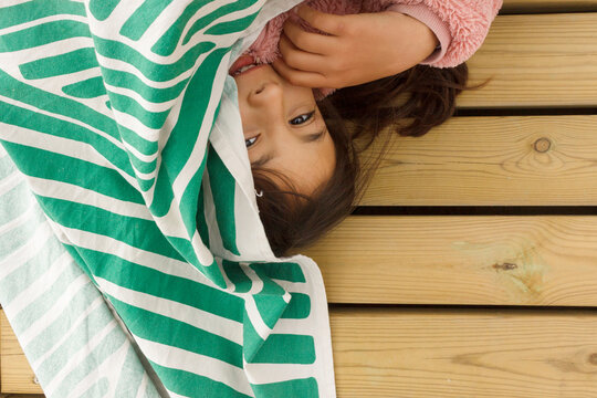 Child Lying on Wooden Floor With a Towel