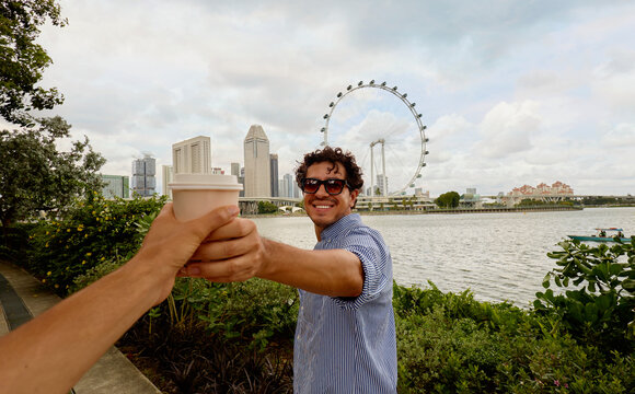 Man holding takeaway coffee near Singapore Flyer waterfront
