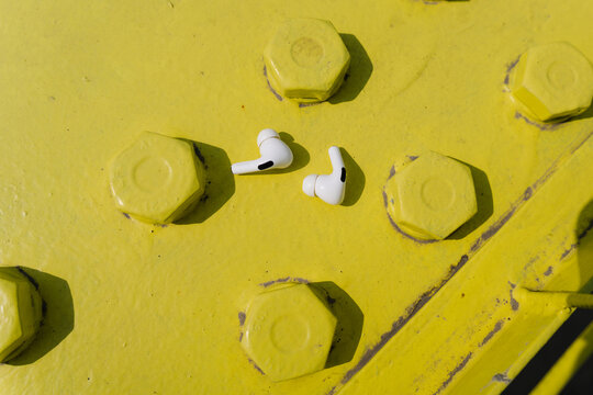 White wireless earbuds on yellow metal surface