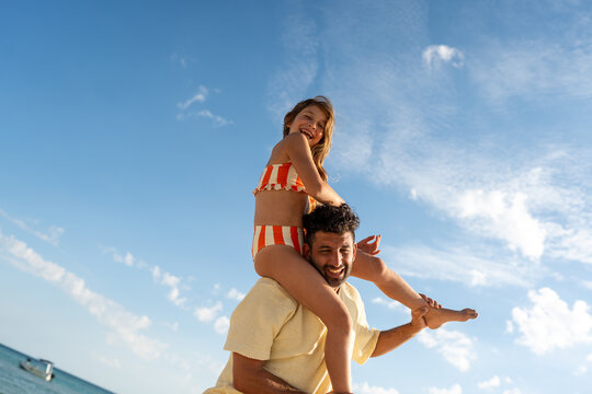 Father carrying child on shoulders at beach