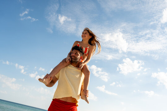 Father carrying child on shoulders at beach