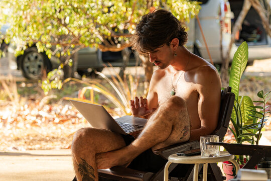 Young man working remotely on laptop outdoors
