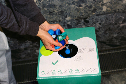  Male's volunteer throwing bottle caps into a container.