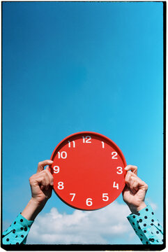 a man holds a clock without hands against the sky, 35mm film