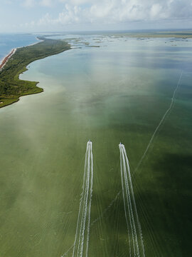 Two motorboats crossing shallow green water