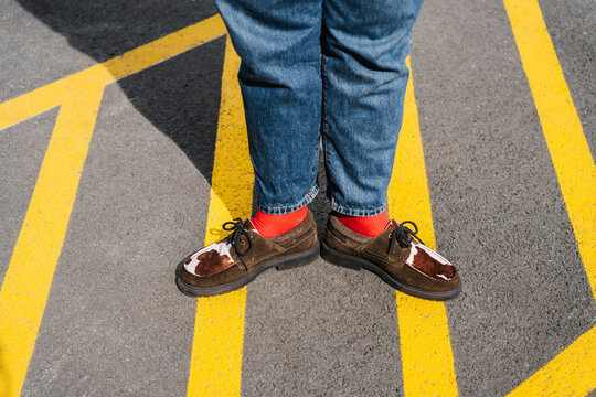 Brown shoes with red socks standing on bright yellow road