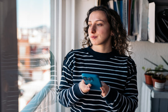 Woman with disability using smartphone near window