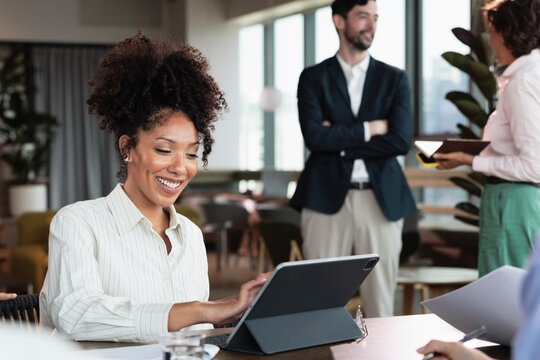 Woman using digital tablet during team meeting in modern office