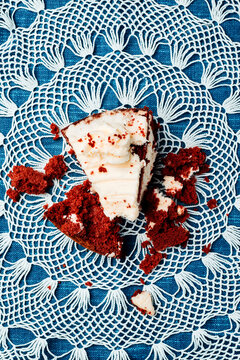 a red velvet cake slice broken into pieces on a crochet doily