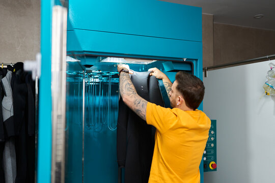 Person placing wetsuit in dive center drying machine
