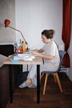 Person working at home on laptop, writing notes