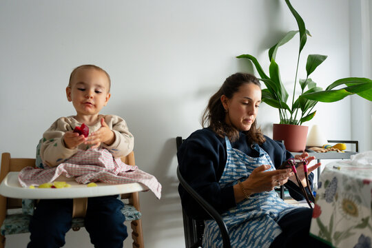 Mother using smartphone while baby eats