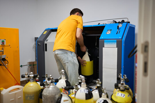 Dive center worker filling scuba tanks with air compressor