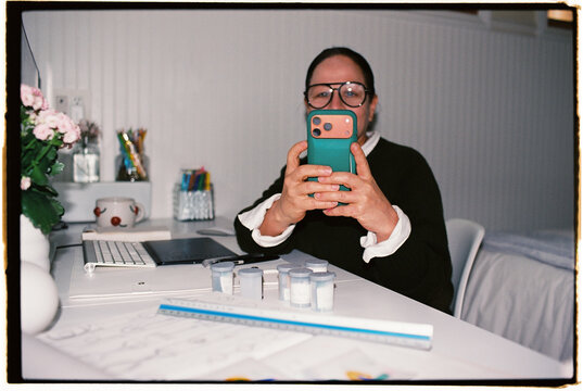 Person Taking a Photo While Sitting at a Desk in a Work Area