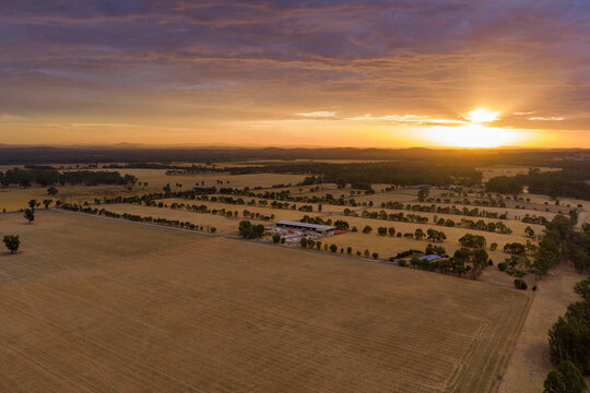 Sun breaking through a gap in clouds at sunset over dry farmland