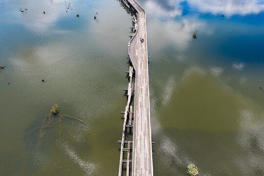 Derelict wooden bridge over sky reflections on a calm inland river