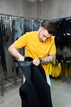 Man preparing wetsuit in a dive shop