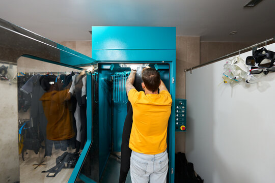 Person placing wetsuit in dive center drying machine
