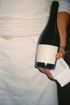 Close-up analog shot, lit by flash, of a man holding a wine bottle